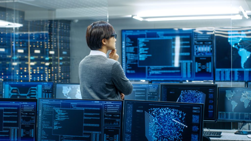 Administrator Stands and Monitors Multiple Computer Displays
